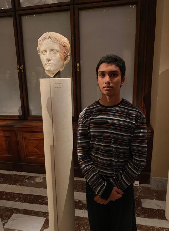 One of our students bends forward in front of a headless marble figure, creating a playful visual alignment.
