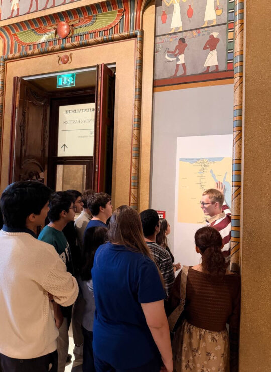 Our students gather around a wall map in the Egyptian gallery as a member of our group gestures towards it.