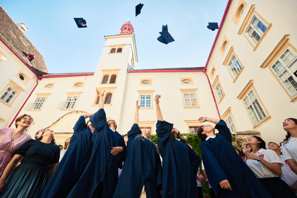 Graduates in navy blue gowns throwing their caps