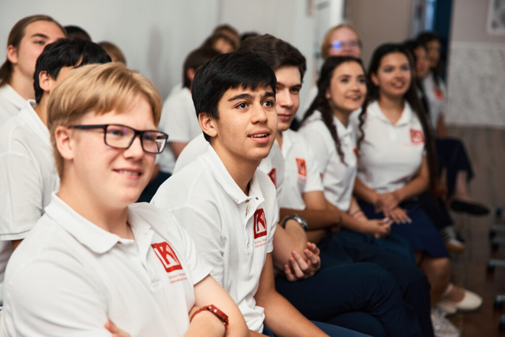 Students in white school polo shirts seated together and looking attentively