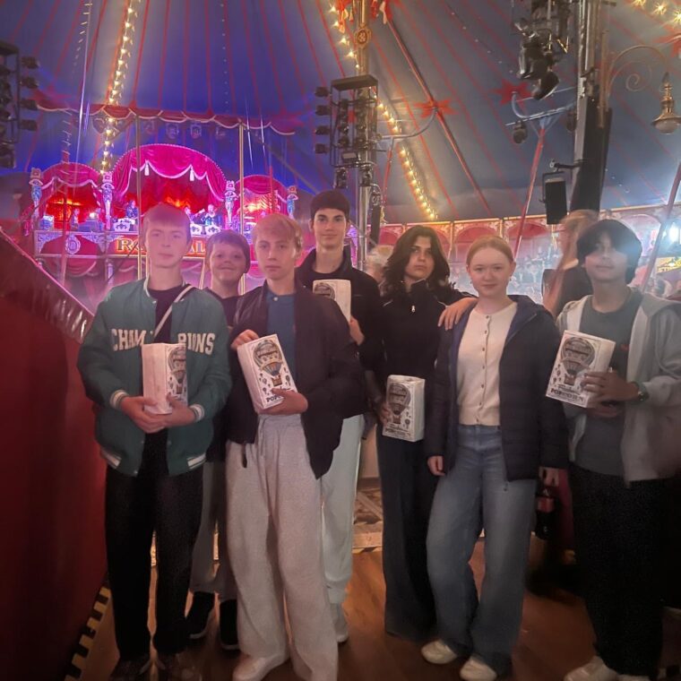 Schloss Krumbach International School students posing inside the colorful Circus Roncalli tent during a school excursion to Vienna.