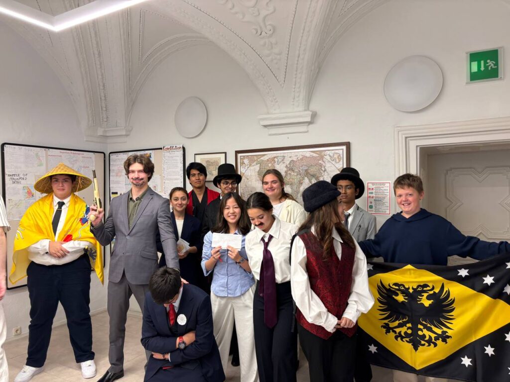 SKIS students posing with a historical-style flag during a school simulation exploring diplomacy before World War I.