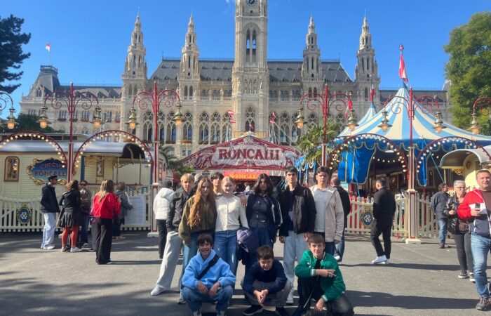 Schloss Krumbach International School students posing in front of Circus Roncalli with Vienna's historic City Hall in the background.