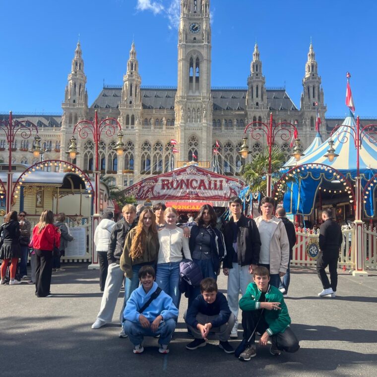 Schloss Krumbach International School students posing in front of Circus Roncalli with Vienna's historic City Hall in the background.