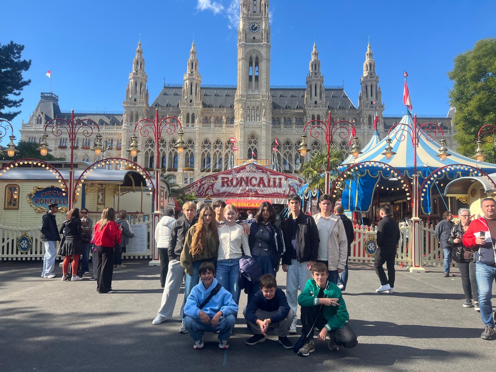 Schloss Krumbach International School students posing in front of Circus Roncalli with Vienna's historic City Hall in the background.